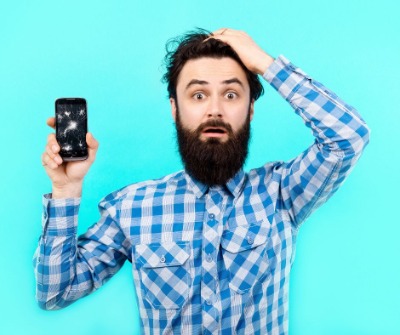 Distressed man holding broken mobile phone